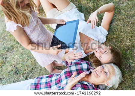 Little girl takes picture of mother and granny with the tablet computer