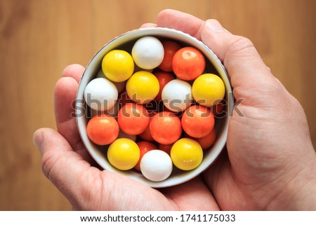 Top view of closeup colorful candies in white bowl on man's hand. Turkish ramadan holiday concept.