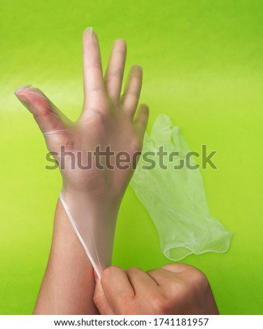Close up of female doctor hand wearing sterile glove. on a green background
