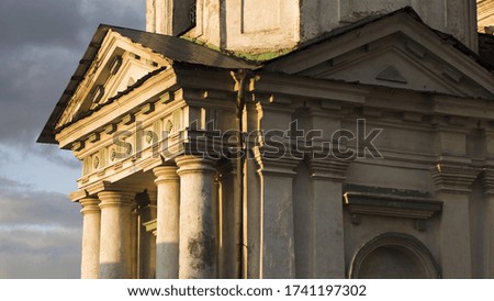 Side view of an ancient church wall. Stock footage. Windows and white walls of the old church or temple facade with chipped paint decorated by columns on cloudy sky background.