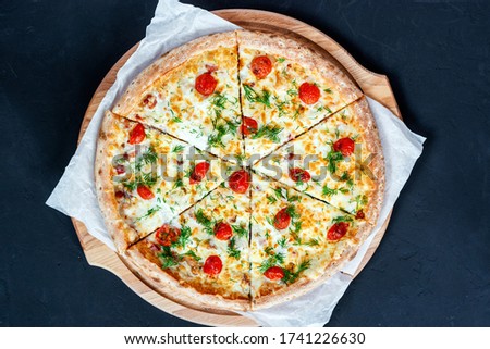 Pizza with Mozzarella cheese, Ham, Tomatoes, pepper, Spices and Fresh greens. Italian pizza on black background. top view