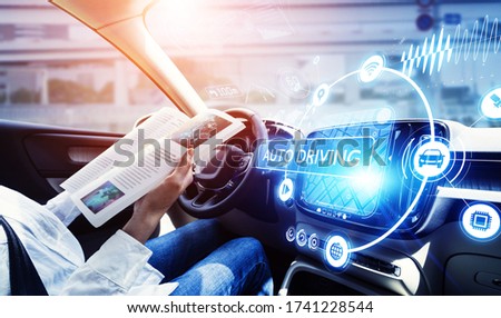 young woman reading a magazine in a autonomous car. driverless car. self-driving vehicle. heads up display. automotive technology. Royalty-Free Stock Photo #1741228544