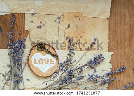 lavender flowers, heart decor, key and old paper on wooden background. vintage romantic composition
