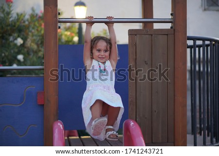 a 4 year old girl plays alone in a children's playground in Finikounda, Greece