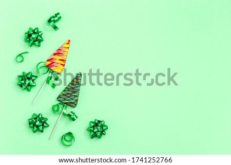 Holiday background with Lollipops shaped like Christmas tree. Creative  New Year Flat lay with sweet candy with stripes on stick on neo mint colored paper with copy space.
