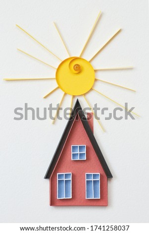 Red paper house with blue windows and sun on white background. Small house made in quilling technique on white background. Hand made of paper. Stay home. Home sweet home.