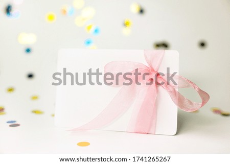 Blank white page mock up card with Pink bow and sparkles confetti on White background. Creative concept, empty greeting card. Copy space