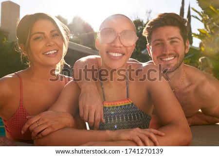 Portrait Of Group Of Friends Outdoors Relaxing In Swimming Pool And Enjoying Summer Pool Party