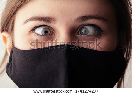 face of young woman in black mask with one eye on one point, life under quarantine and epidemic, crazy madness concept, mood fooling around, humor