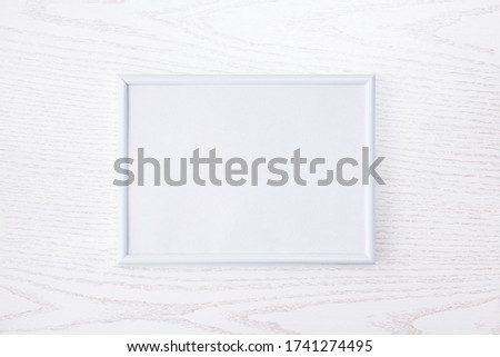White simple picture frame on a white wooden texture.