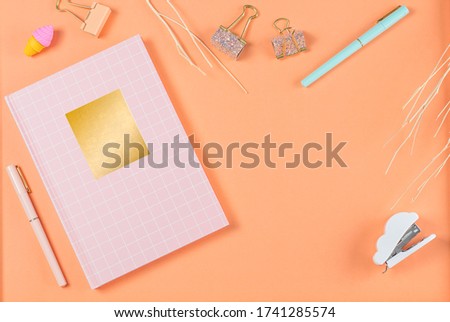 flat lay stationery on work desk in orange pastel background	
