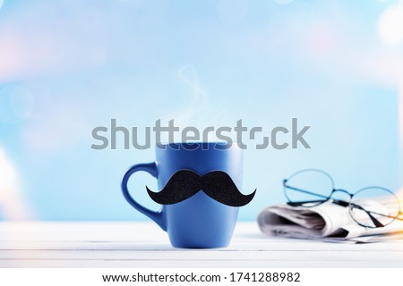 Cup of coffee with mustache and newspaper for creative morning breakfast on Happy Fathers Day. 