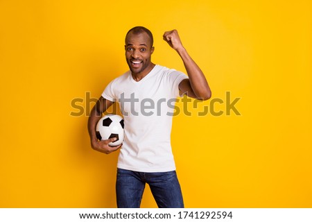 Yeah we win. Positive ecstatic afro american football fan guy hold soccer ball support national team celebrate victory raise fists wear white t-shirt isolated bright shine color background Royalty-Free Stock Photo #1741292594