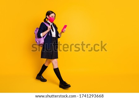 Full size profile side photo high school teenager go walk lesson use smartphone chatting wear black blazer jacket skirt long socks backpack medical mask isolated yellow color background