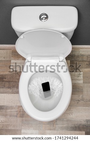 Smartphone dropped into toilet bowl indoors, top view