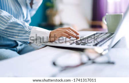 Close up picture of females hands on the keyboard. Young woman working with laptop sitting in modern living room at home. Technology, freelance and work concept.