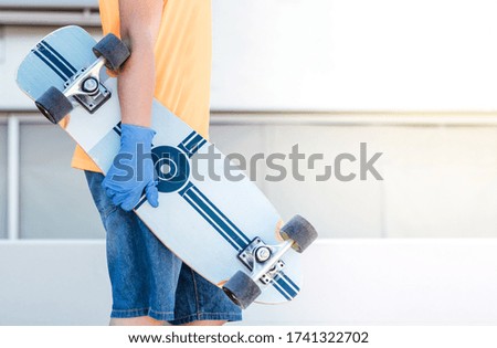 Child holding a skateboard with protective gloves in the street. Playing after the confinement of the covid19. Copy space design