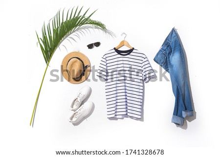 Set of sunglasses, straw hat, green palm and white shoes, and tshrit   hanging and blue jeans on white background