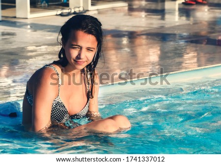 Happy smiling girl having fun and playing in the swimming pool at the summer day time, summertime outdoor