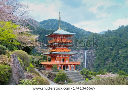 Kumano Nachi Taisha Shrine (three-story pagoda) which Nachi no Taki waterfall is background 
 during cherry blossom season in Wakayama, Japan.