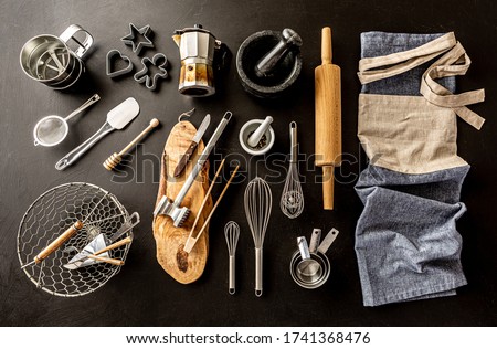 Kitchen utensils (cooking tools) and chef’s apron on black chalkboard background. Kitchenware collection captured from above (top view, flat lay). Royalty-Free Stock Photo #1741368476