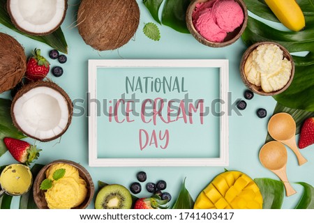 National ice cream day 19 july concept. Tropical fruits and plants with variety of ice cream in coconut shells on blue background, flat lay, text National Ice Cream Day