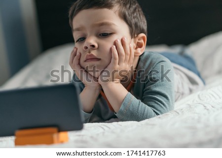 selective focus of thoughtful, attentive boy looking webinar on smartphone