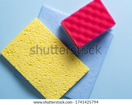 Top view of cleaning sponges of different colors and sizes laid out on a blue background