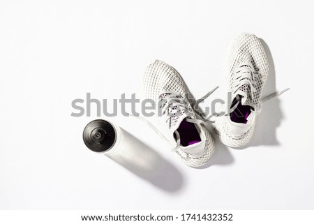 White running shoes, water bottle on a white background under the natural light of the morning sun. Concept of jogging, running, hard workout. Banner. Flat lay, top view