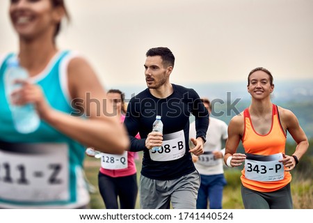 Group of athletes running marathon in nature. Focus is on young couple. Royalty-Free Stock Photo #1741440524