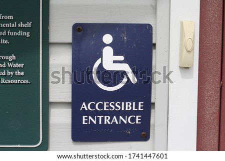 A handicap accessible entrance sign outside of a community center in a local park.