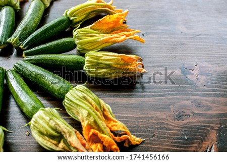 Zucchini and courgette flowers arranged in a sunburst pattern on a dark wooden table
