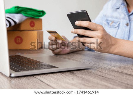 Side view photo of people shopping using laptop computer placed on wooden table with full of boxes and mock up credit cards for shopping online and electronic commerce for the digital life style.