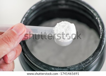L-Glutamine supplement. Man holding scoop with L-Glutamine powder inside. Close up. Royalty-Free Stock Photo #1741465691