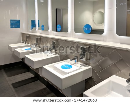 Distance stickers and signs fixed over the sinks, mirrors in a public toilet for the people to follow social distancing to avoid infection of coronavirus disease.