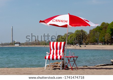 Canada Day celebration on the beach in Toronto with a Canadian flag umbrella with the Toronto skyline in the distance