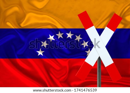 customs sign, stop, attention on the background of the silk national flag of the country of Venezuela, the concept of border and customs control, violation of the state border, tourism restrictions