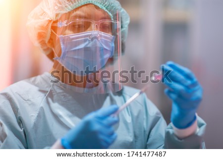 The doctor or lab technician scientist in PPE Personal Protective Equipment holding vacine test, Vaccine injection, World immunization and International HPV Royalty-Free Stock Photo #1741477487
