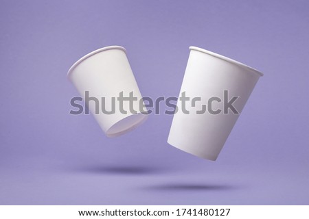 White paper cup of coffee colored background.  Flying paper cup on violet background. Isolated for mock up Royalty-Free Stock Photo #1741480127