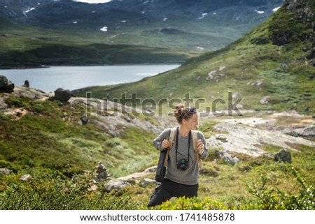 Young woman traveler professional photographer with a camera on neck admires the scenery during a hike, Norway, beautiful northern nature