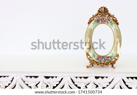 Image of baroque vintage empty photo frame over wooden table. For mockup, can be used for photography montage