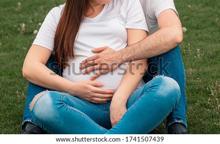 Happy and young pregnant couple expecting baby. Father hands lying on the tummy. Round belly. New life concept.