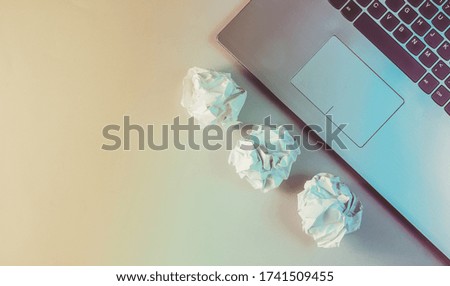 Laptop, crumpled paper balls close up. Holographic light. Modern business concept.