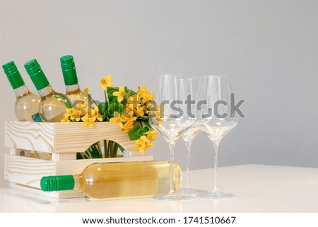 Wine glasses, bottles, yellow flowers in wooden box