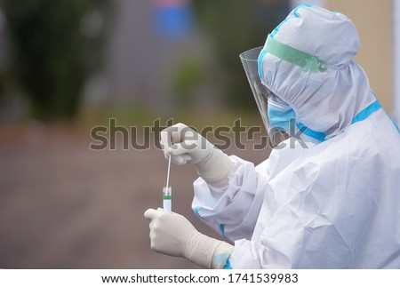 People wearing protective suit for COVID-19 handles a pharyngeal exudate/ swab collection kit for the coronavirus. Test tube for taking OP NP patient specimen sample,PCR DNA testing protocol process