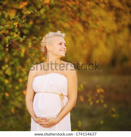 beautiful pregnant young woman outside, warm sunny picture