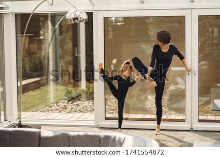 Girl is engaged in gymnastics. Family in a yoga studio. Kid in a black sportwear.