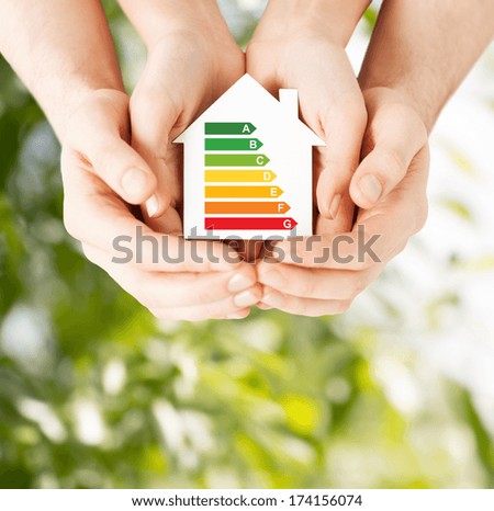 energy saving, real estate and family home concept - closeup of couple hands holding white paper house with energy efficiency rating Royalty-Free Stock Photo #174156074