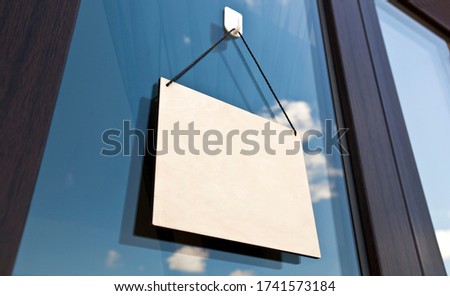 The wooden sign without text hanging on the door in cafe
