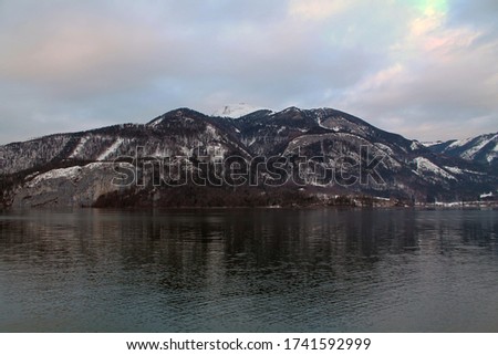 
Landscape of Wolfganfsee lake in Austria, surrounded by small mountains. The photo was taken in Wintertime during sunset time.